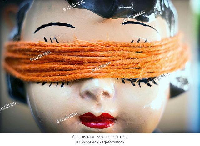 Head of antique porcelain doll with a orange rope covering her eyes