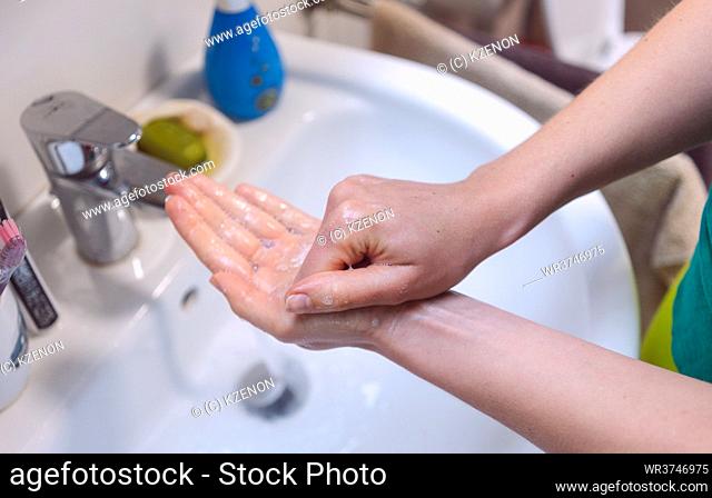 Woman washing her hands thoroughly in bathroom