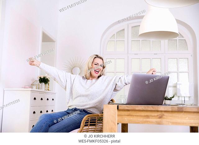 Portrait of happy blond mature woman with laptop at home