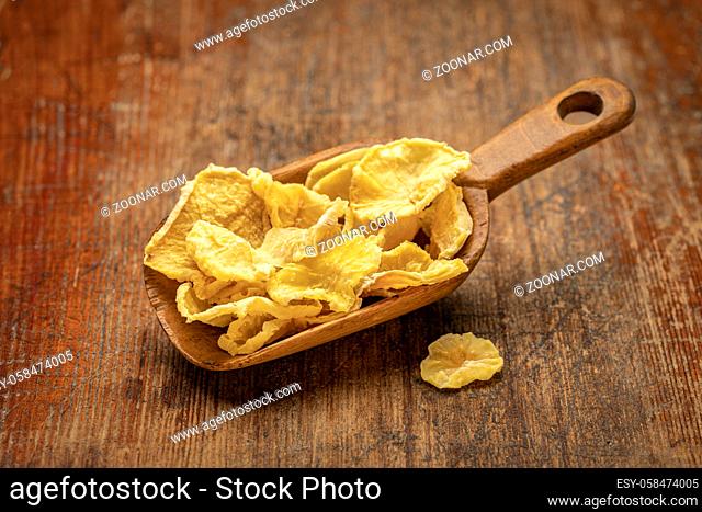 Dried slices of yacon tuber ion a rustic wooden scoop against weathered wood. Yacon contains inulin, a complex sugar, which promotes healthy probiotics