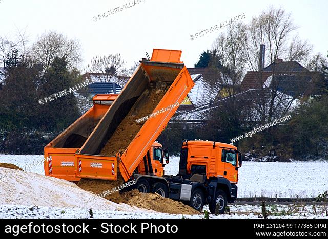 04 December 2023, Saxony-Anhalt, Niedere Börde: Trucks dump sand on the construction site for the next section of the A14 north of Magdeburg