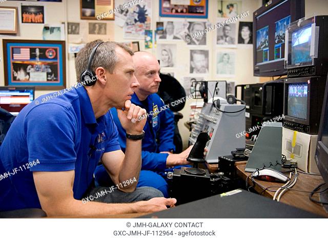 NASA astronauts Mark Kelly (background), STS-134 commander; and Andrew Feustel, mission specialist, use the virtual reality lab in the Space Vehicle Mock-up...