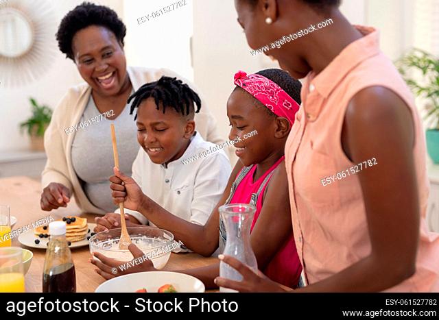 African american mother and grandmother teaching girl and boy cooking in the kitchen