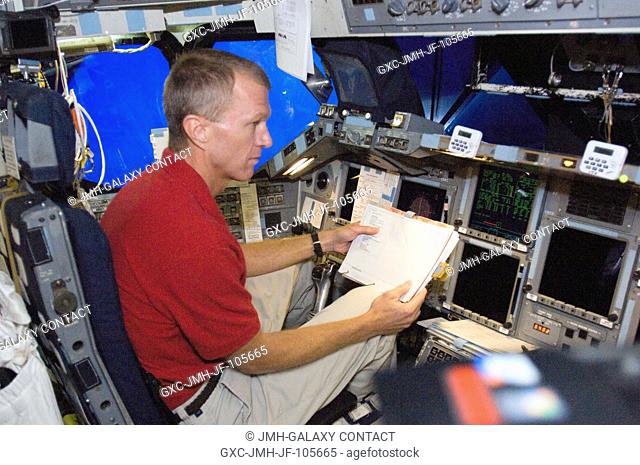Astronaut Brent W. Jett Jr., STS-115 commander, looks over a procedures checklist at the commander's station during a training session in the shuttle mission...