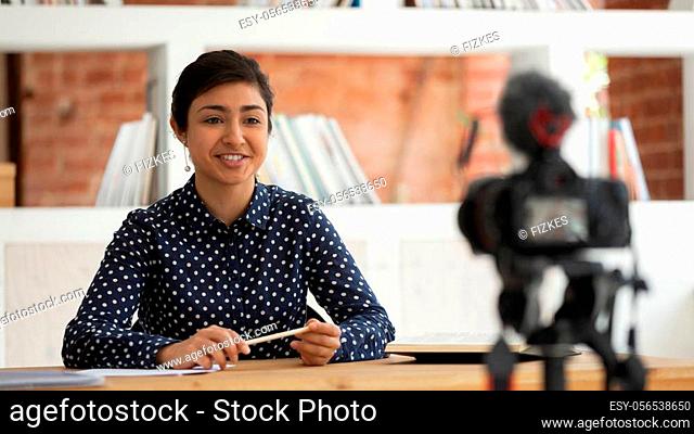 Confident happy indian millennial girl sitting in front of camera, recording self-introduction or educational video for online university course