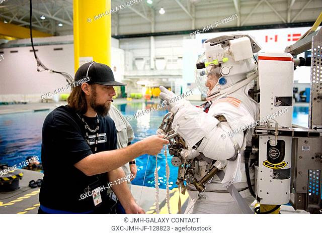Japan Aerospace Exploration Agency (JAXA) astronaut Satoshi Furukawa, Expedition 2829 flight engineer, gets help in the donning of a training version of his...