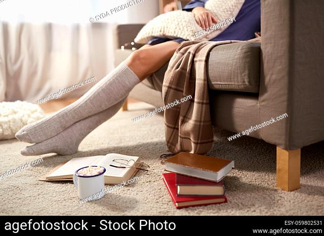woman with books and drink on floor at home