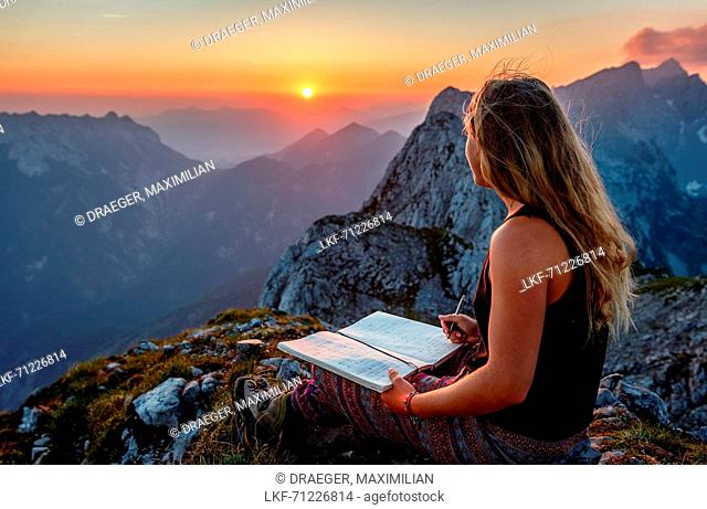 Young woman at the summit, writing into a book, Scheffauer, Wilder Kaiser, Tyrol, Austria