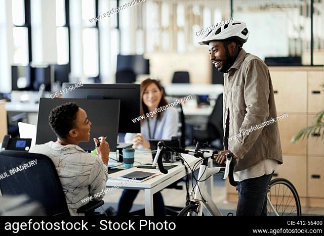 Businessman with bicycle talking to businesswomen in office