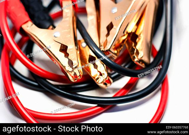 Close up of red and black car battery jumper cable, isolated on white background. Boost cable. Focus on metal