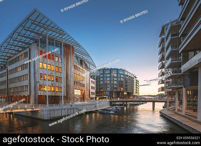 Oslo, Norway. Night View Embankment And Residential Multi-storey Houses In Aker Brygge District. Summer Evening. Residential Area Reflected In Sea Waters