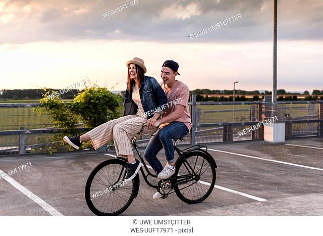Happy young couple together on a bicycle on parking deck