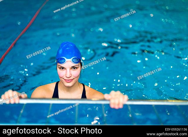 Female swimmer in an indoor swimming pool - looking at the camera, smiling wholeheartedly (shallow DOF; color toned image)(shallow DOF)