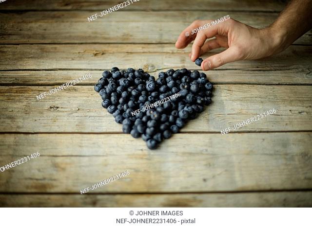Hand making heart out of blueberries