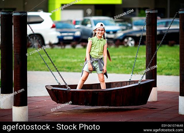 Child girl on a swing in the form of a boat. Selective focus
