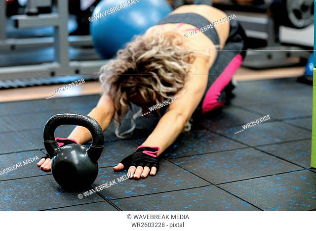 Woman performing stretching exercise with kettlebell
