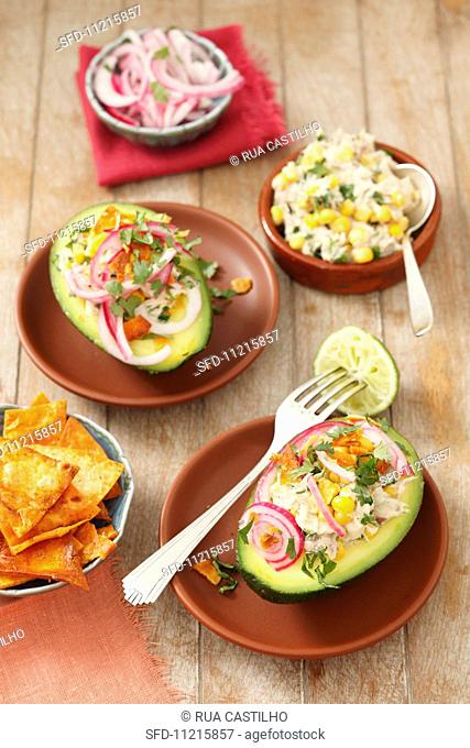 Avocado filled with smoked mackerel and a sweetcorn salad, topped with red onions and served with tortilla chips