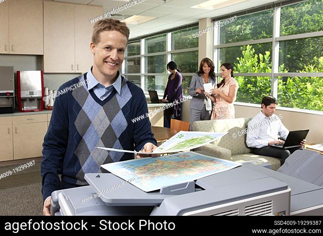 Portrait of a Caucasian man standing at a printer while in breakroom