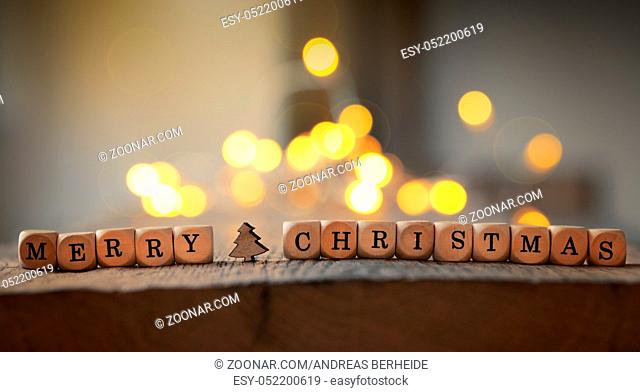 Christmas background with the words Merry Christmas on a wooden table, blurred Christmas lights in the back