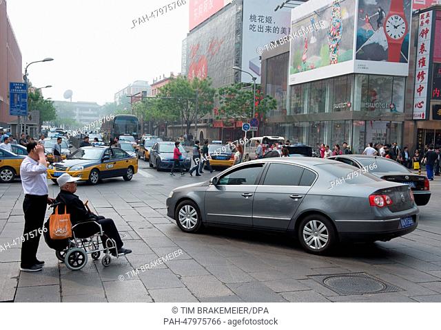 An elderly man is pushed in a wheelchair across an intersection in Beijing, China, 14 April 2014. Photo: Tim Brakemeier/dpa | usage worldwide
