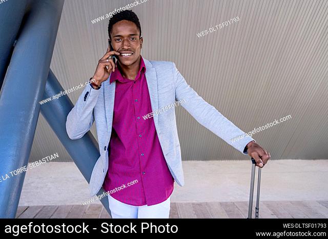 Smiling businessman talking on mobile phone by structure