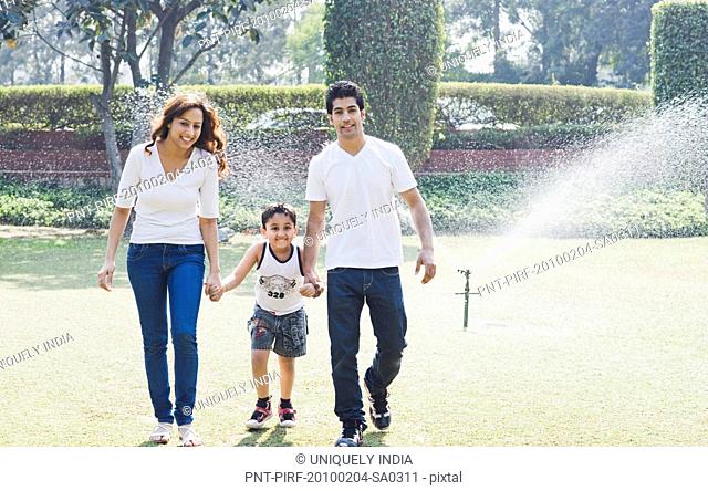 Couple enjoying in front of a sprinkler with their son, Gurgaon, Haryana, India