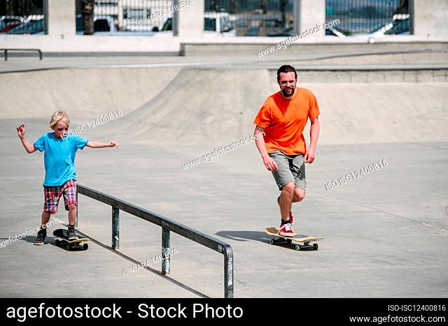 USA, California, Ventura, Father and son (8-9) skateboarding in skate park