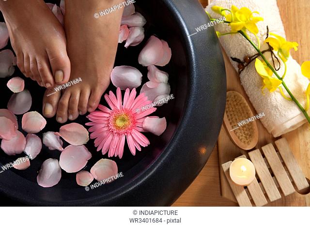 Close-up of woman's feet in a bowl of water and petals at spa