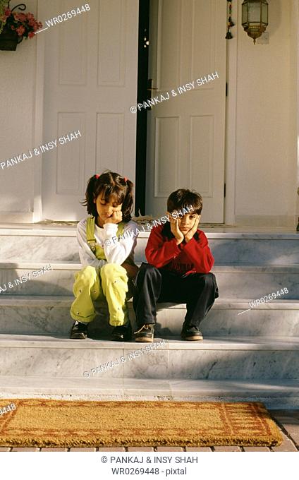 Two children wait patiently at the doorstep
