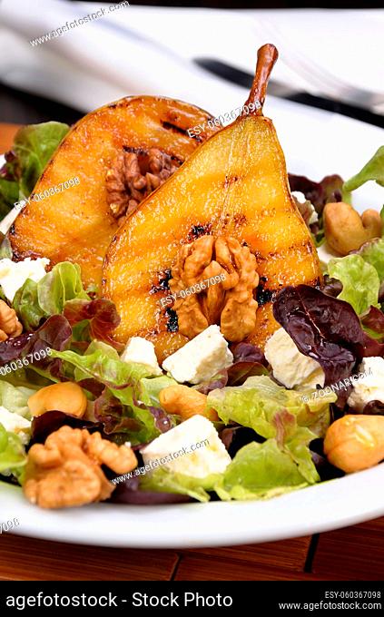 Salad of lettuce with  walnuts, cashews, slices feta, halves of caramelized pear