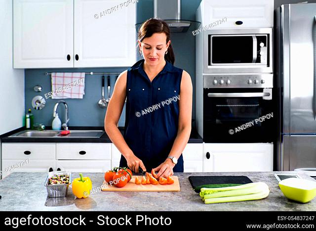 Woman Cooking Dinner At Home Cutting Vegetables