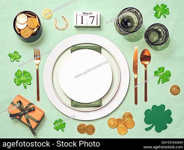 Beautiful festive table setting for St.Patrick's day with cutlery and lucky symbols. Top view of Saint Patrick's day holiday table with green linen tablecloth