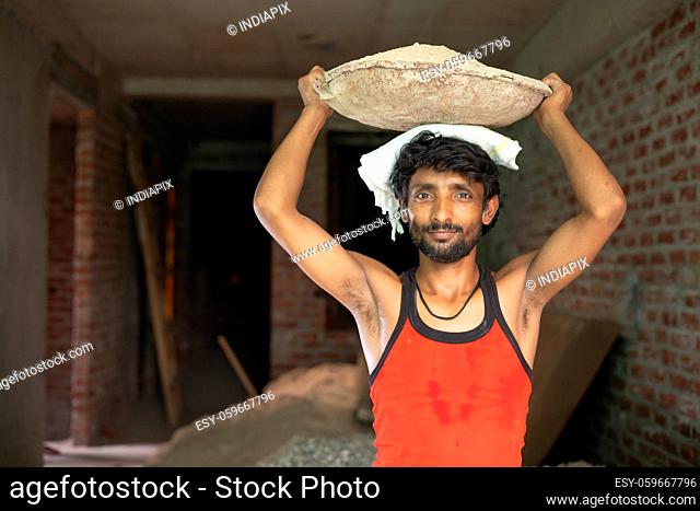 A LABOURER STANDING WHILE CARRYING LOAD ON HEAD