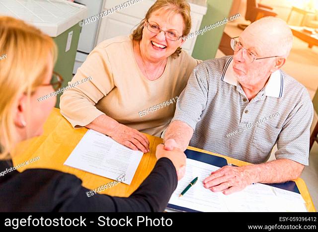 Senior Adult Couple Going Over Documents in Their Home with Agent At Signing
