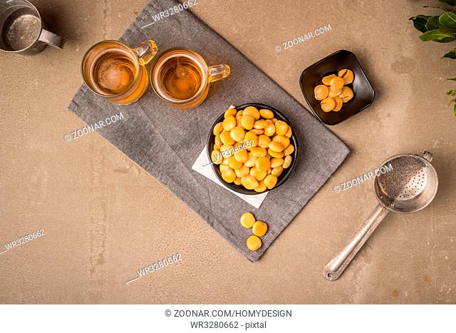 Tasty lupins in metal mug and glass of beer on wooden table top