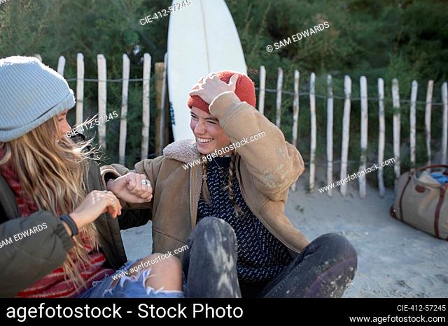 Amigos felices de las mujeres jóvenes riendo en la playa