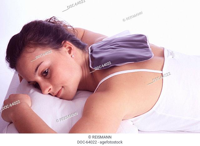 Woman with mud pillow on her neck against muscle pains