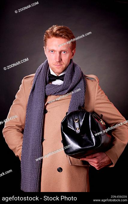 elegant man with hand bag wearing a beige coat