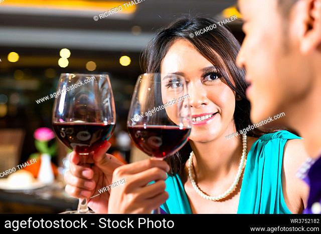 Close up of Asian couple toasting with red wine