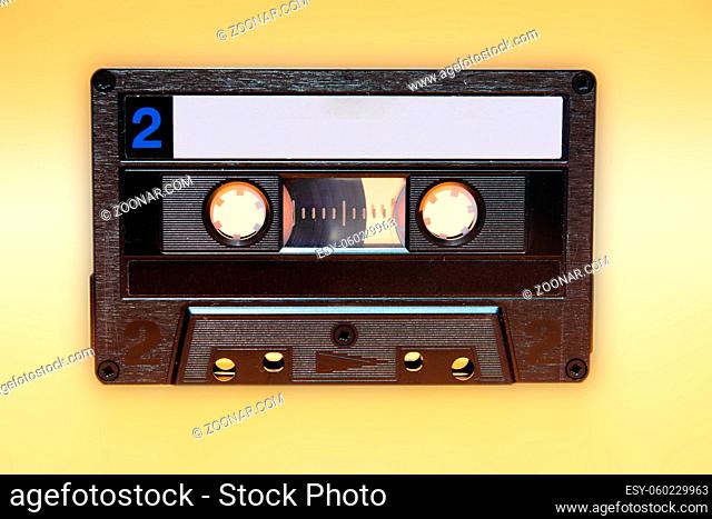 Retro audio cassette tape on yellow background. Front view of side two and traces of dust with minor scratches