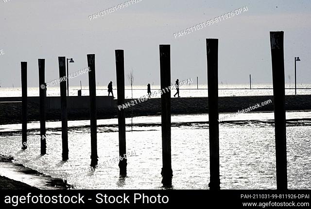 18 October 2021, Lower Saxony, Juist: People walk across the pier to the sea mark on the East Frisian island of Juist, one of the island's landmarks