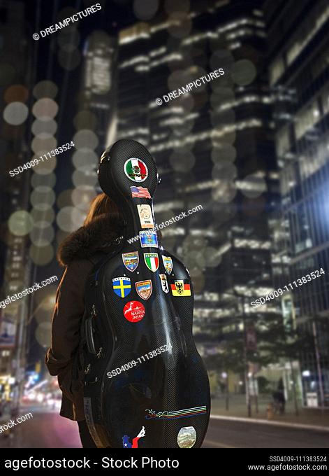 Musician carrying cello case in city