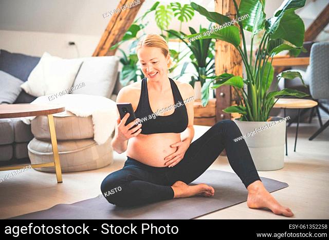 Young happy and cheerful beautiful pregnant woman chating to family and friends on mobile phone while staying fit, sporty and active on her maternity leave