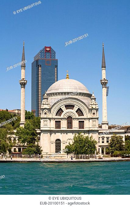 Dolmabahce Mosque beside the Bosphorus with modern building behind