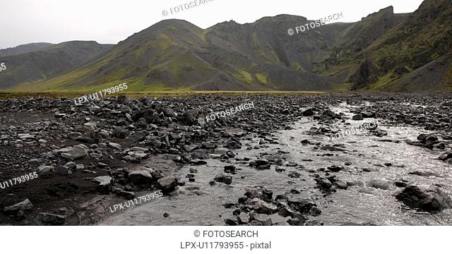 Rocky river bed below rugged mountains