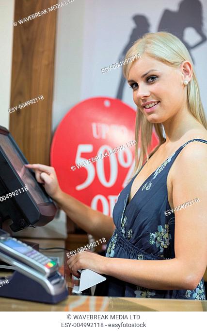 Woman is standing behind counter while typing at the till