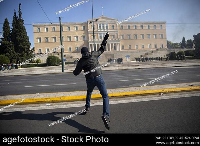 09 November 2022, Greece, Athen: A demonstrator throws a gasoline bomb at riot police during a 24-hour general strike in Athens