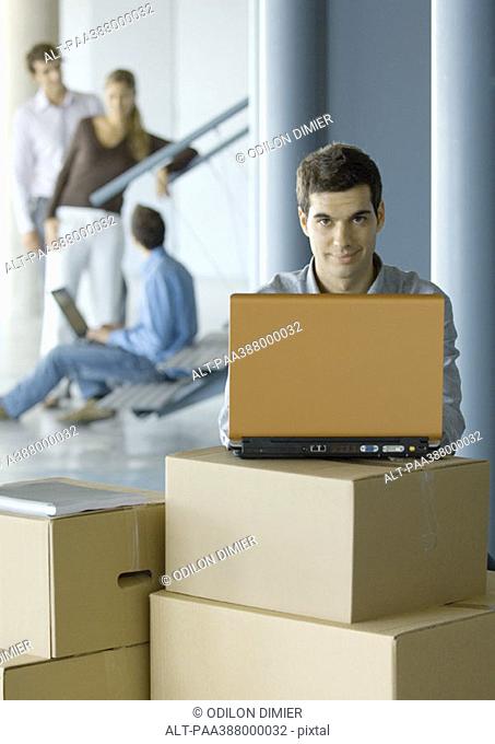 Businessman using laptop on cardboard box