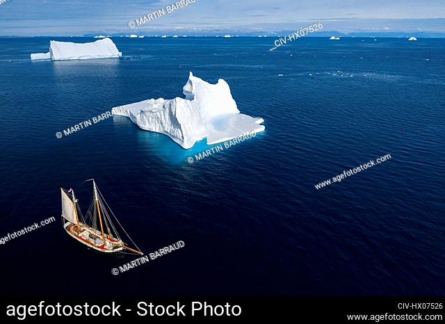 Ship sailing past icebergs on sunny blue ocean Greenland