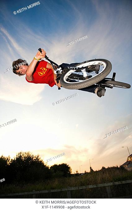 Teenage boy on trials bike at a skateboard park performing aerobatic stunts, Aberystwyth Wales UK